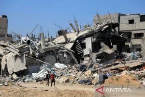 Warga Palestina melintas di jalan yang dikelilingi bangunan yang hancur akibat serangan Israel di Kota Khan Younis, Jalur Gaza Selatan, Palestina, Jumat (12/4/2024). 