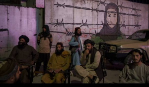 Anggota kelompok Taliban berdiri di depan mural yang menggambarkan perempuan terkekang di balik kawat berduri, Selasa, 21 September 2021. 